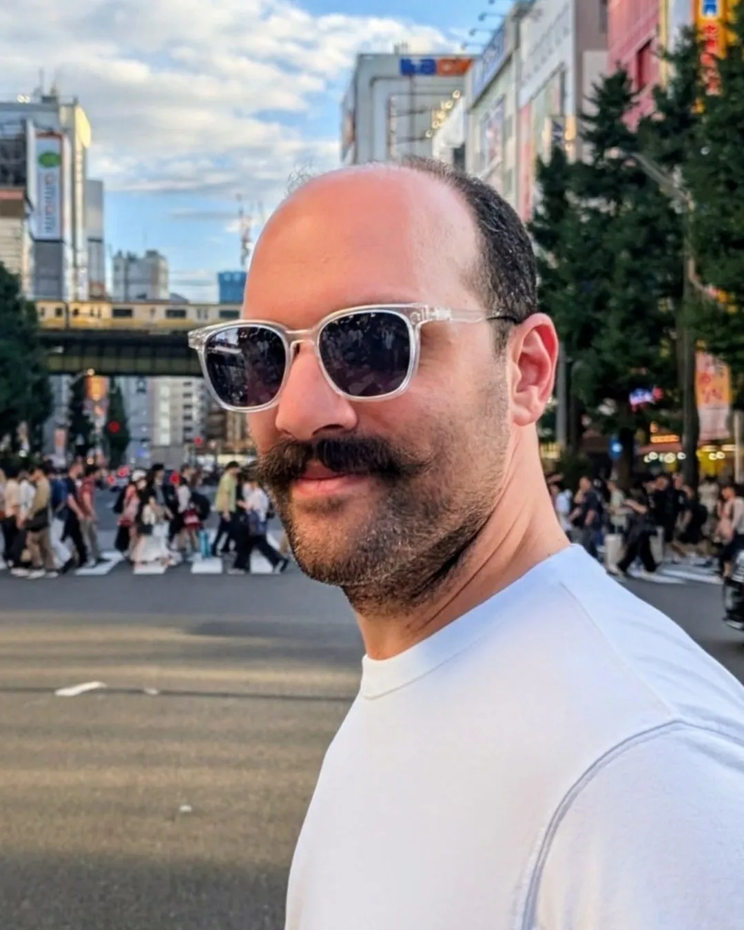 Bahman in Tokyo, smiling, in sunglasses and a white T-shirt